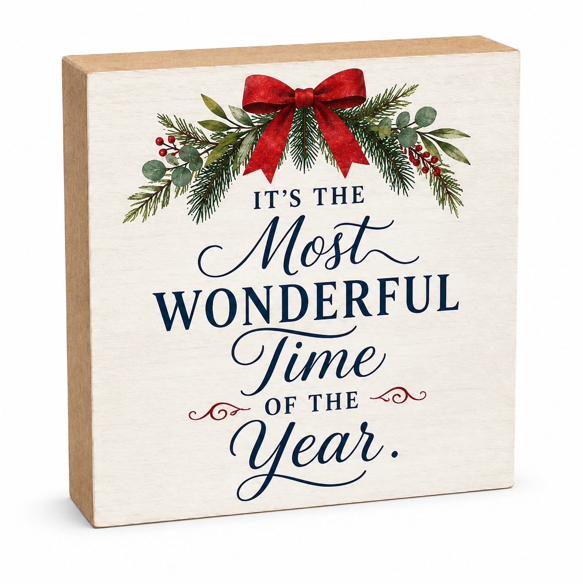 A square decorative wooden sign with a natural wood side and front panel printed with the phrase “IT’S THE Most WONDERFUL Time OF THE Year.” The text is styled in navy and red script, topped with a green pine garland, red bow, and small red berries, shown on a clean white background.