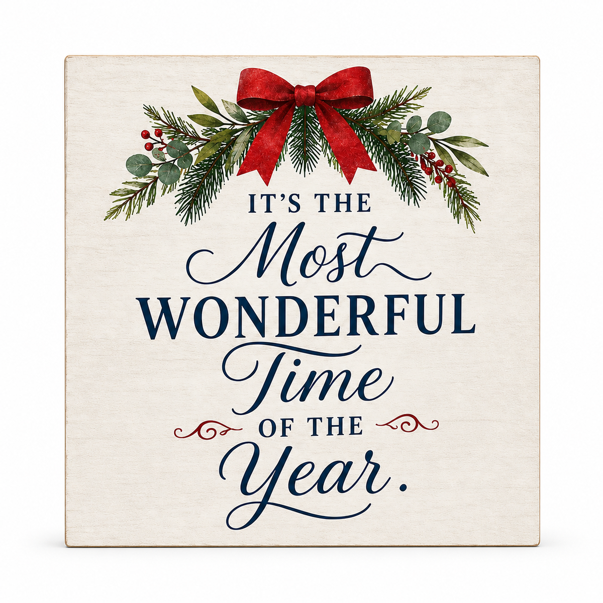 A square decorative sign with a cream background featuring the phrase 'IT'S THE Most WONDERFUL Time OF THE Year.' in navy script and serif lettering, topped with a red bow, green pine branches, and small red berries.