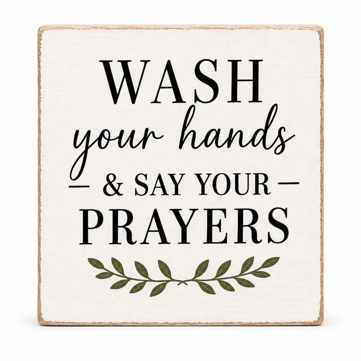 A square decorative wooden sign with a distressed off-white background and natural wood edges. The sign features the text 'WASH your hands & SAY YOUR PRAYERS' in black lettering, with a small olive green leafy branch graphic at the bottom, set against a plain white background.