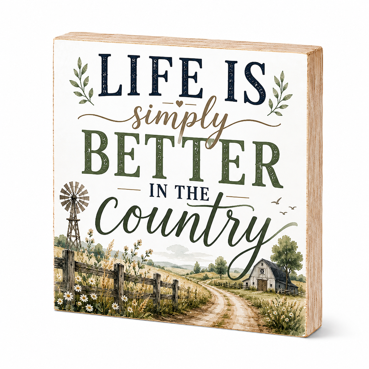 A square decorative wooden sign with a rustic country design. The top portion features the text 'LIFE IS simply BETTER IN THE country' in dark navy, beige, and olive green lettering on a cream background, decorated with small leafy sprigs.