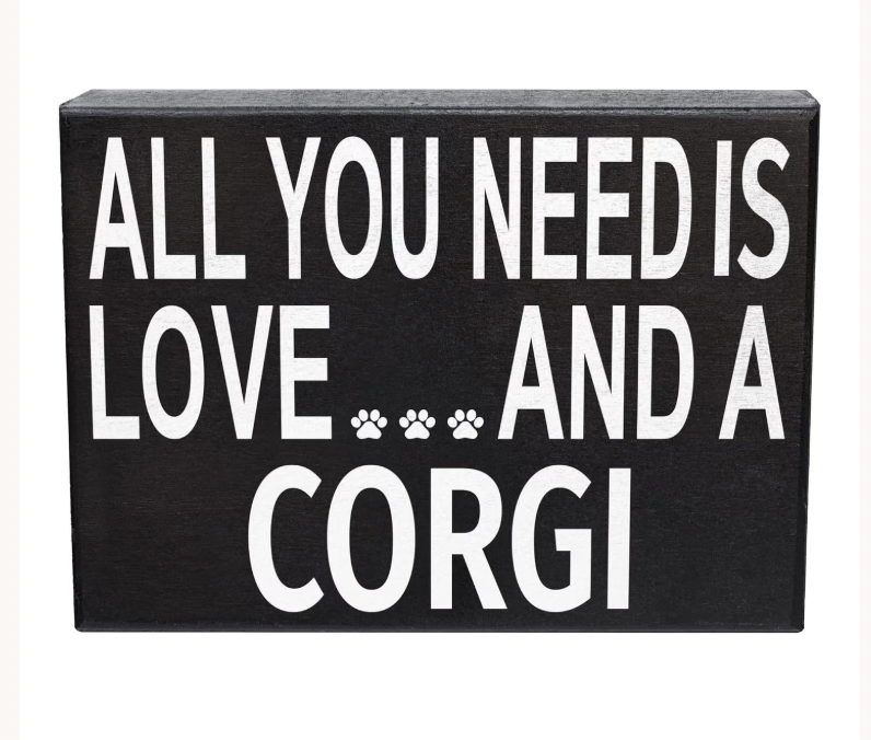 A rectangular black sign with bold white text reading 'ALL YOU NEED IS LOVE.