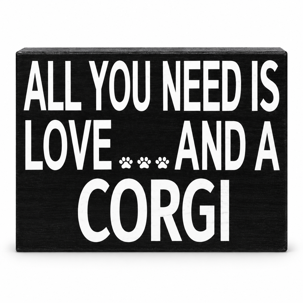 A rectangular black decorative sign with bold white text reading 'ALL YOU NEED IS LOVE.