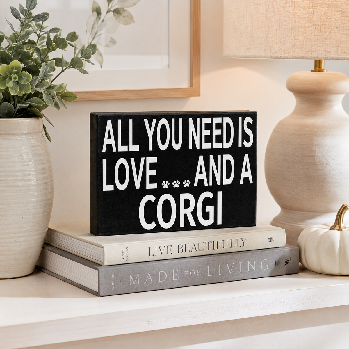 A black rectangular decorative sign with bold white text reading 'ALL YOU NEED IS LOVE.