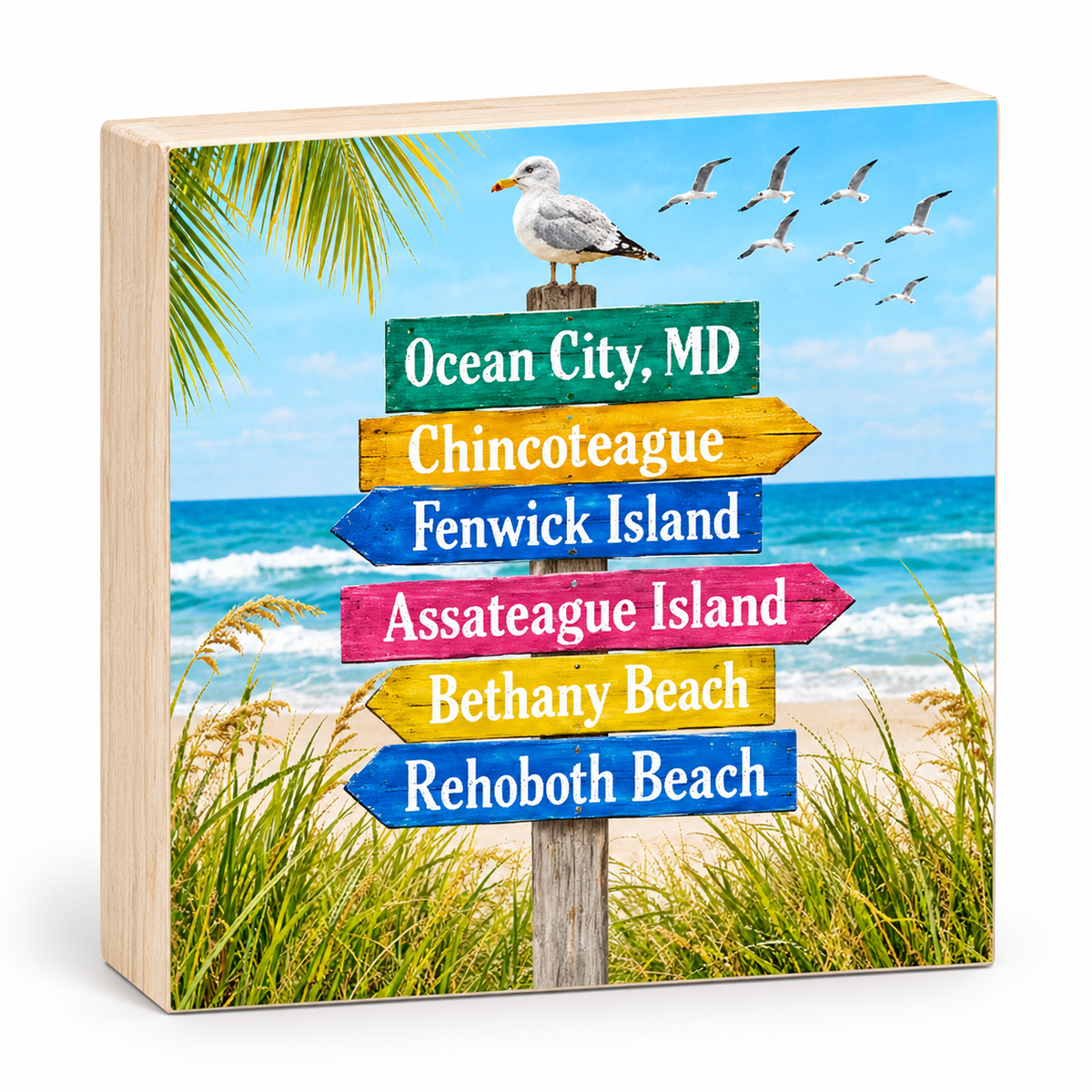 A square wooden decorative block featuring a beach scene with a colorful directional signpost reading Ocean City, MD, Chincoteague, Fenwick Island, Assateague Island, Bethany Beach, and Rehoboth Beach, with a seagull on top and the ocean and sand in the background.