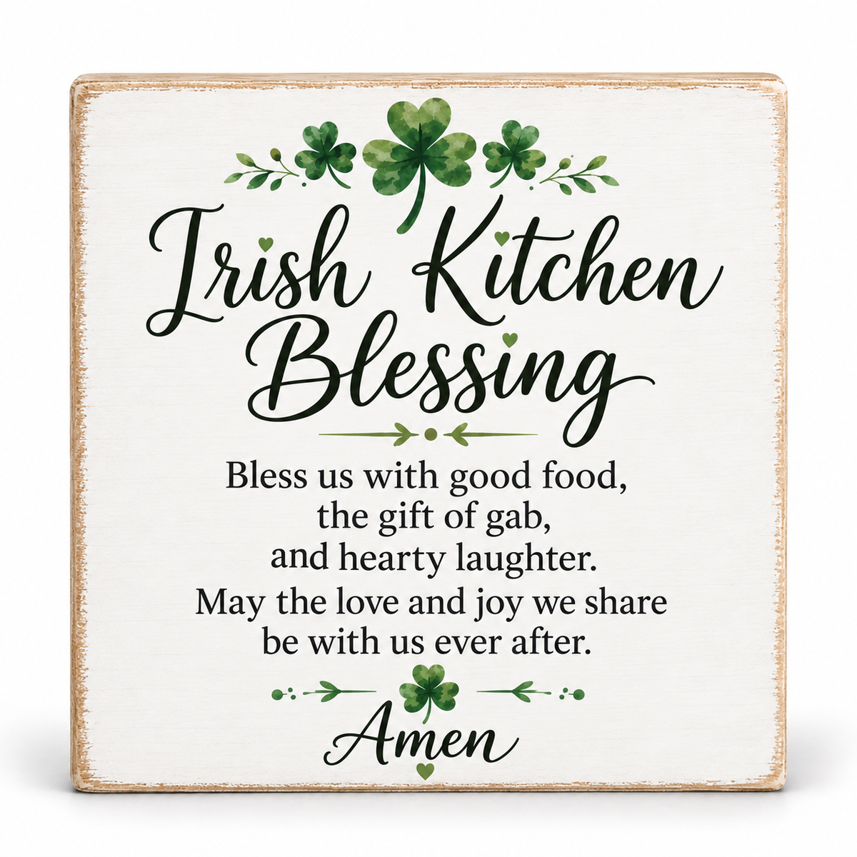 A square decorative sign with a distressed white background and rustic beige edges, featuring the text 'Irish Kitchen Blessing' in black script with green shamrock and leaf accents, plus a poem and the word 'Amen' at the bottom.
