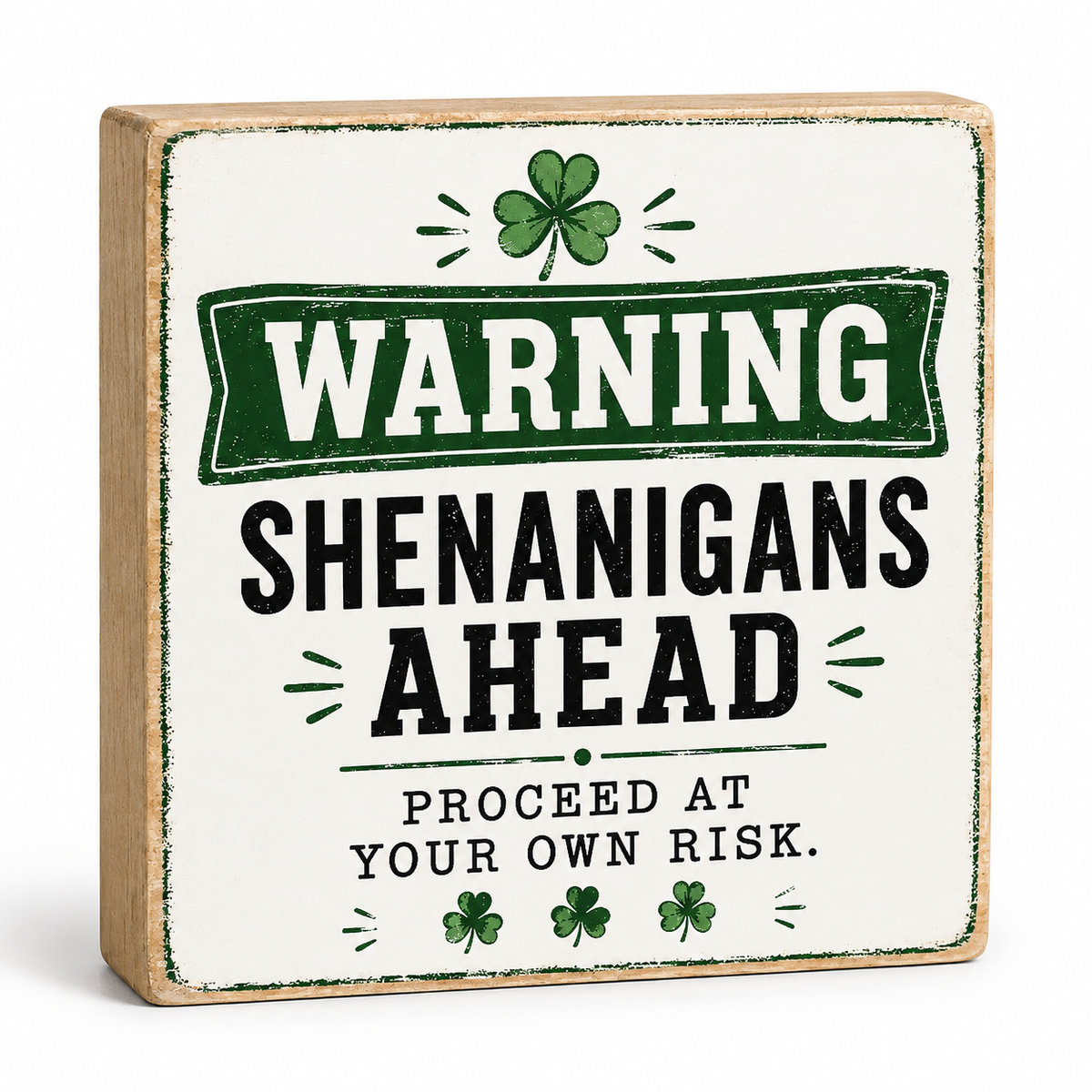 A square decorative wooden sign with a distressed off-white face and natural wood edges. The sign features a green and black warning-style graphic reading “WARNING SHENANIGANS AHEAD PROCEED AT YOUR OWN RISK,” with shamrock motifs above and below.