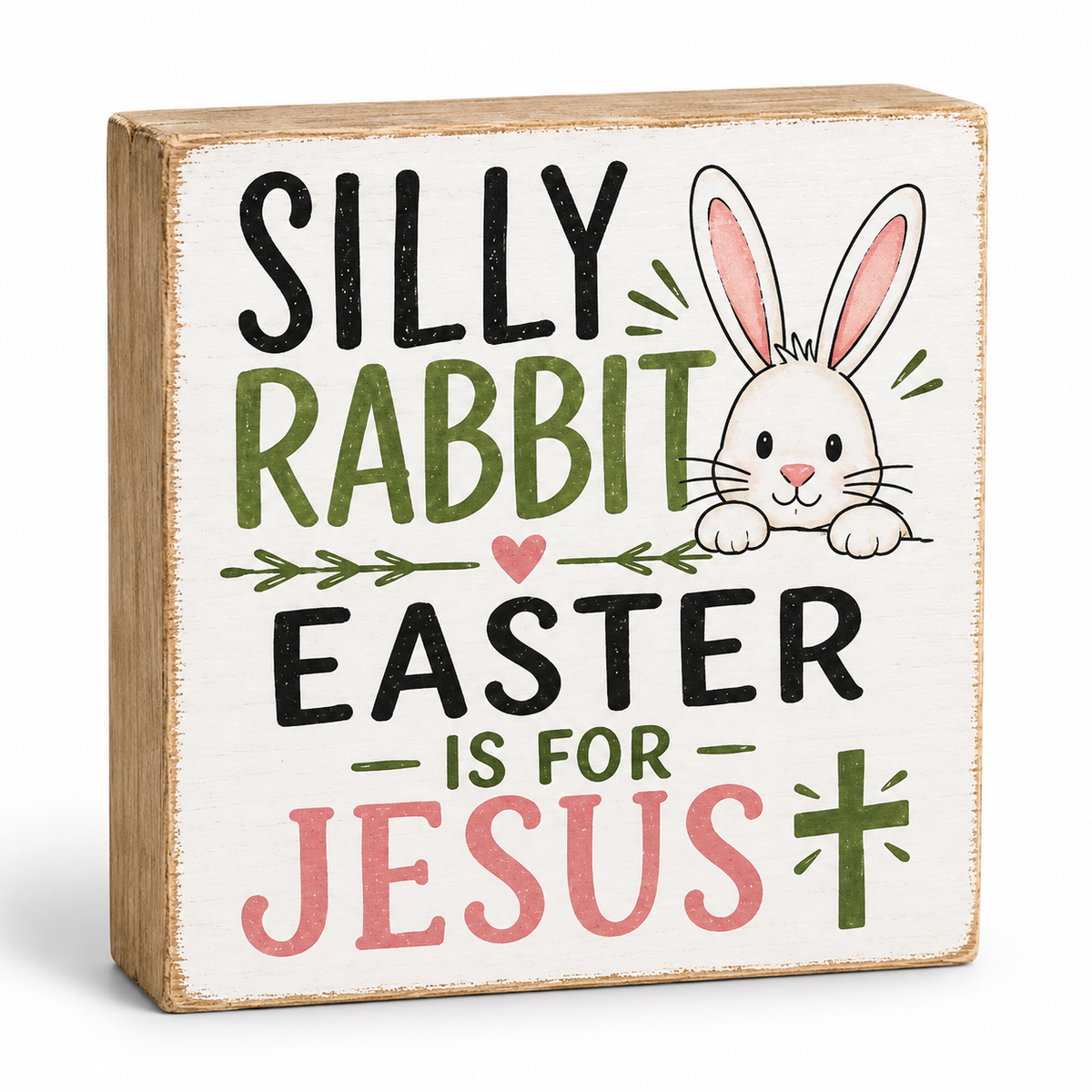 A square wooden decorative sign with a distressed white face and natural wood edges, featuring the text 'SILLY RABBIT EASTER IS FOR JESUS' in black, green, and pink lettering, alongside a cartoon white rabbit with pink inner ears.