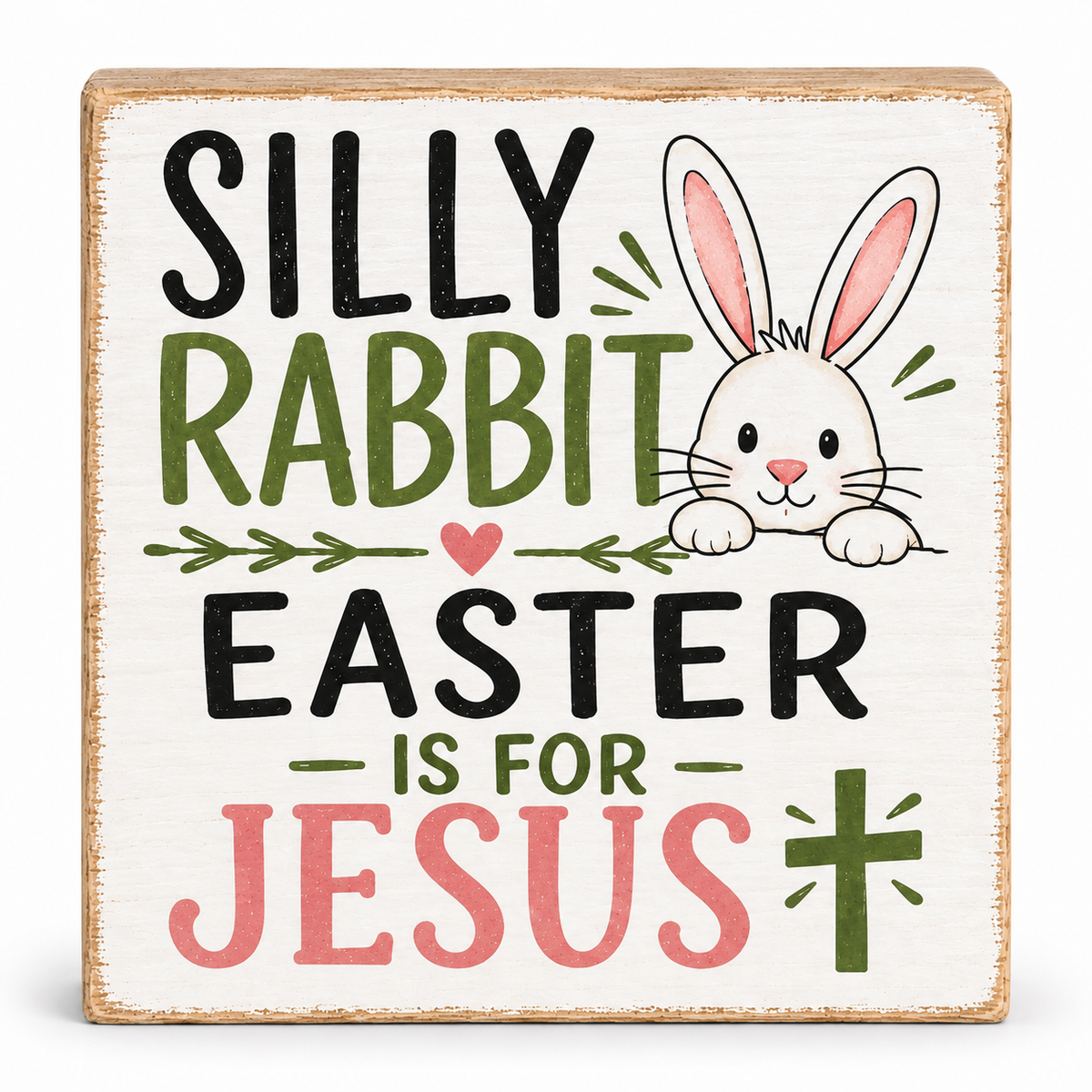 A square decorative wooden sign with a distressed white background and natural wood edges. The sign features the text 'SILLY RABBIT EASTER IS FOR JESUS' in black, green, and pink lettering, accompanied by a cartoon white rabbit with pink inner ears peeking over the top right.