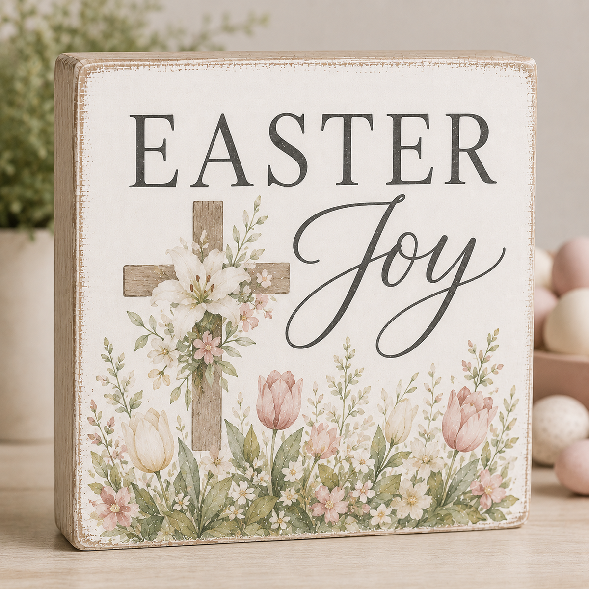 Decorative sign with 'Easter Joy' text, cross, and flowers on a wooden background.