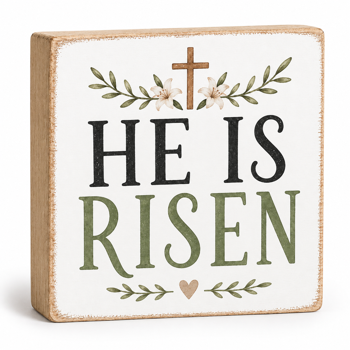 A square decorative wooden sign with a distressed white face and natural wood edges. The sign reads “HE IS RISEN” in large black and muted green lettering, with a small brown cross, white flowers, and green leafy branches above and below.