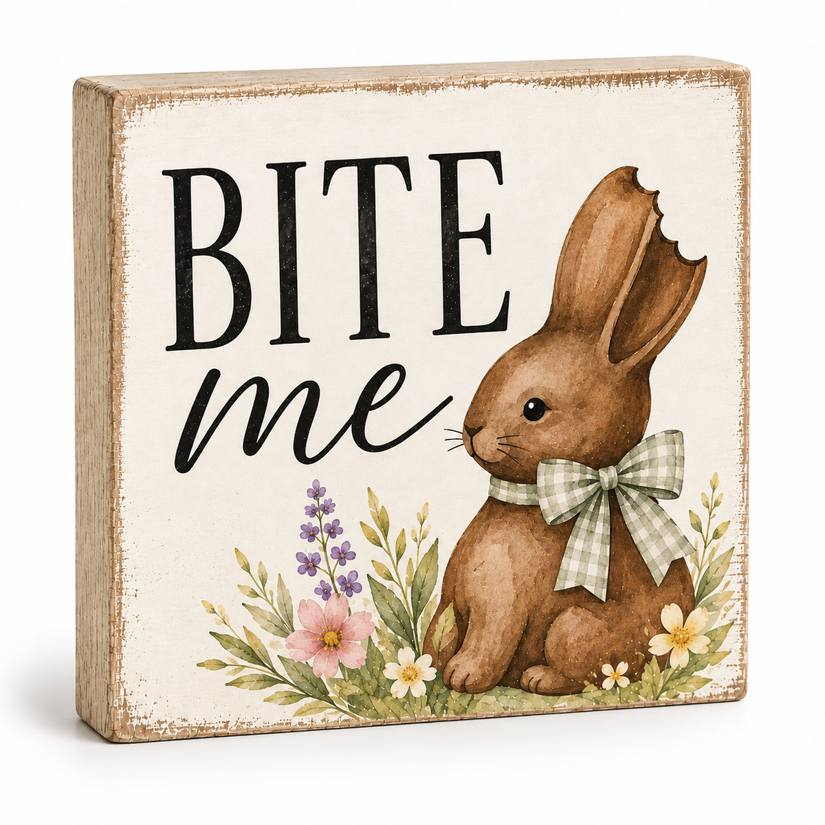 A square decorative wooden sign with a distressed cream background, featuring the words “BITE me” in black lettering next to an illustration of a brown bunny wearing a green-and-white gingham bow, with small flowers at the bottom.
