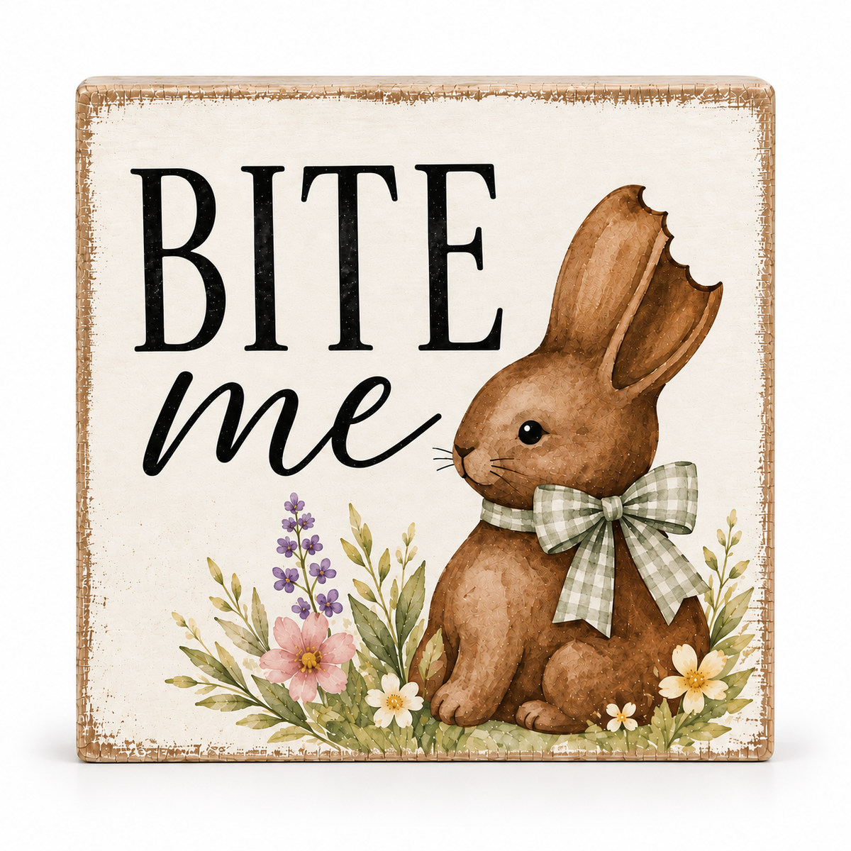 A square decorative sign with a distressed cream background, featuring the words “BITE me” in black lettering, an illustrated brown bunny wearing a green-and-white gingham bow, and small flowers at the bottom. The sign has a rustic wood-toned border and is photographed against a plain white background.