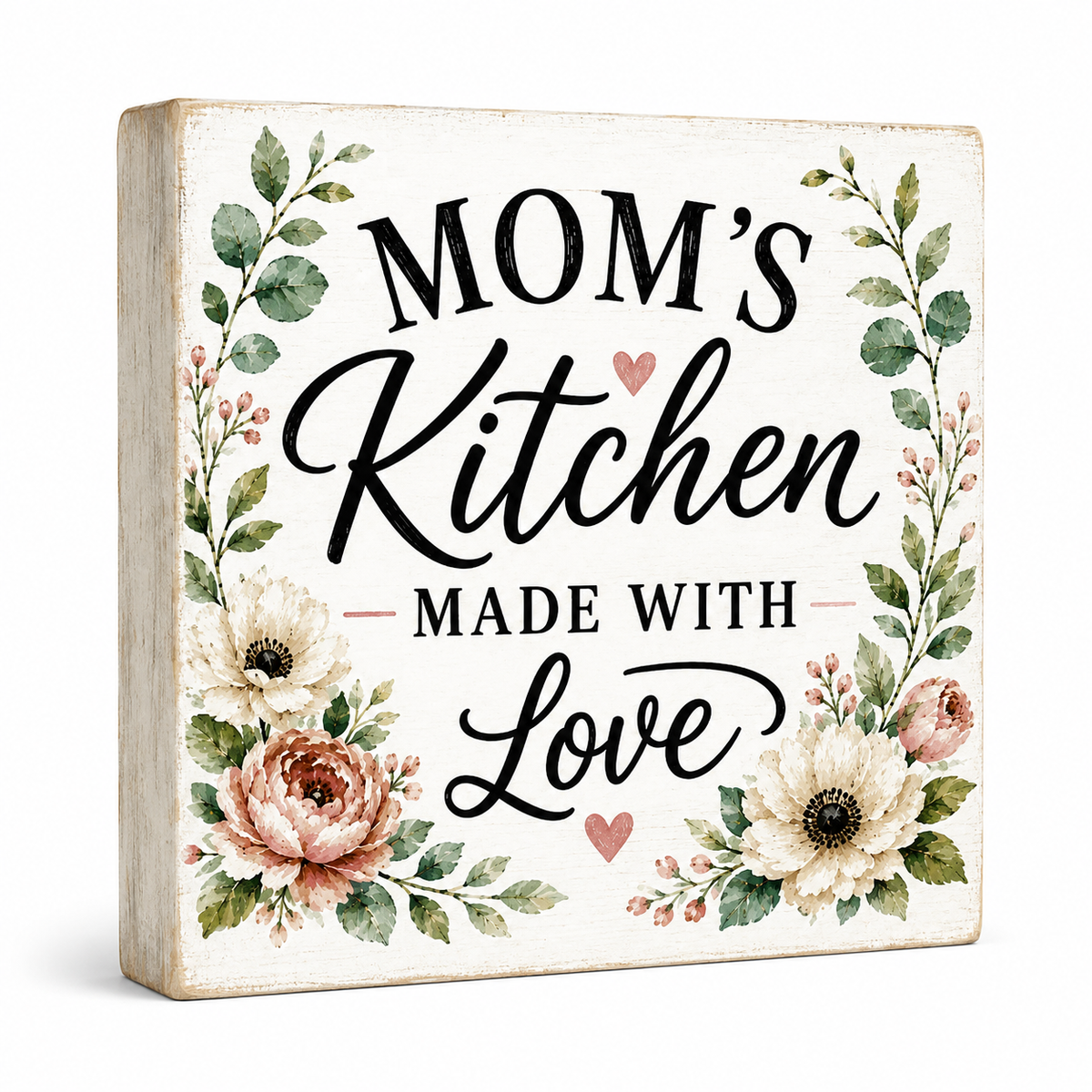 A square decorative sign with a distressed cream background featuring the text 'MOM'S Kitchen MADE WITH Love' in black script and serif lettering, surrounded by watercolor-style floral illustrations in green, blush pink, and cream. The sign is photographed on a clean white background with a soft shadow.