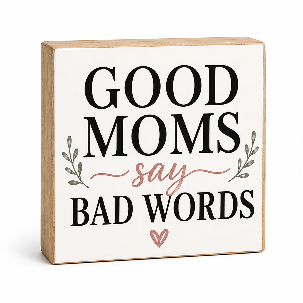 A square decorative wooden sign with a light natural wood border and an off-white face. The sign reads “GOOD MOMS say BAD WORDS” in black lettering, with a dusty pink script word and matching pink heart accent, plus small gray leafy side details.