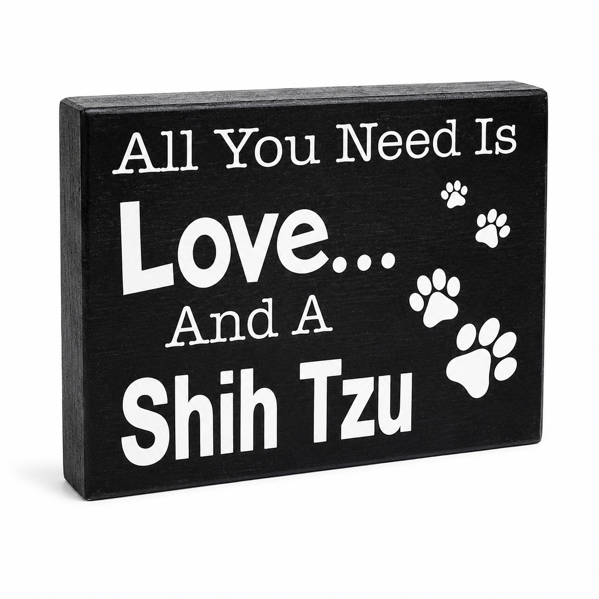 A rectangular black wooden sign with white text reading 'All You Need Is Love.