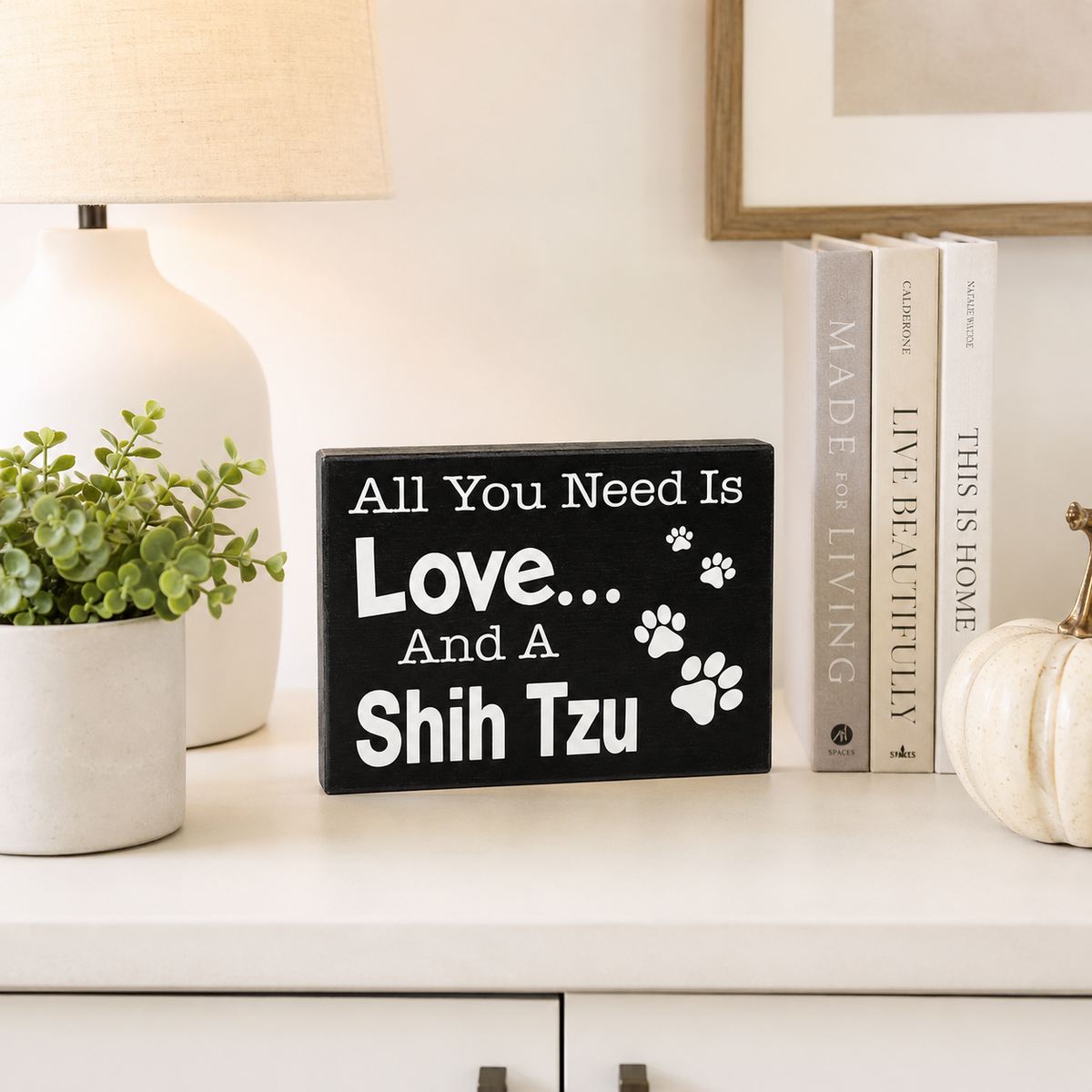 A black rectangular decorative sign with white text reading 'All You Need Is Love.