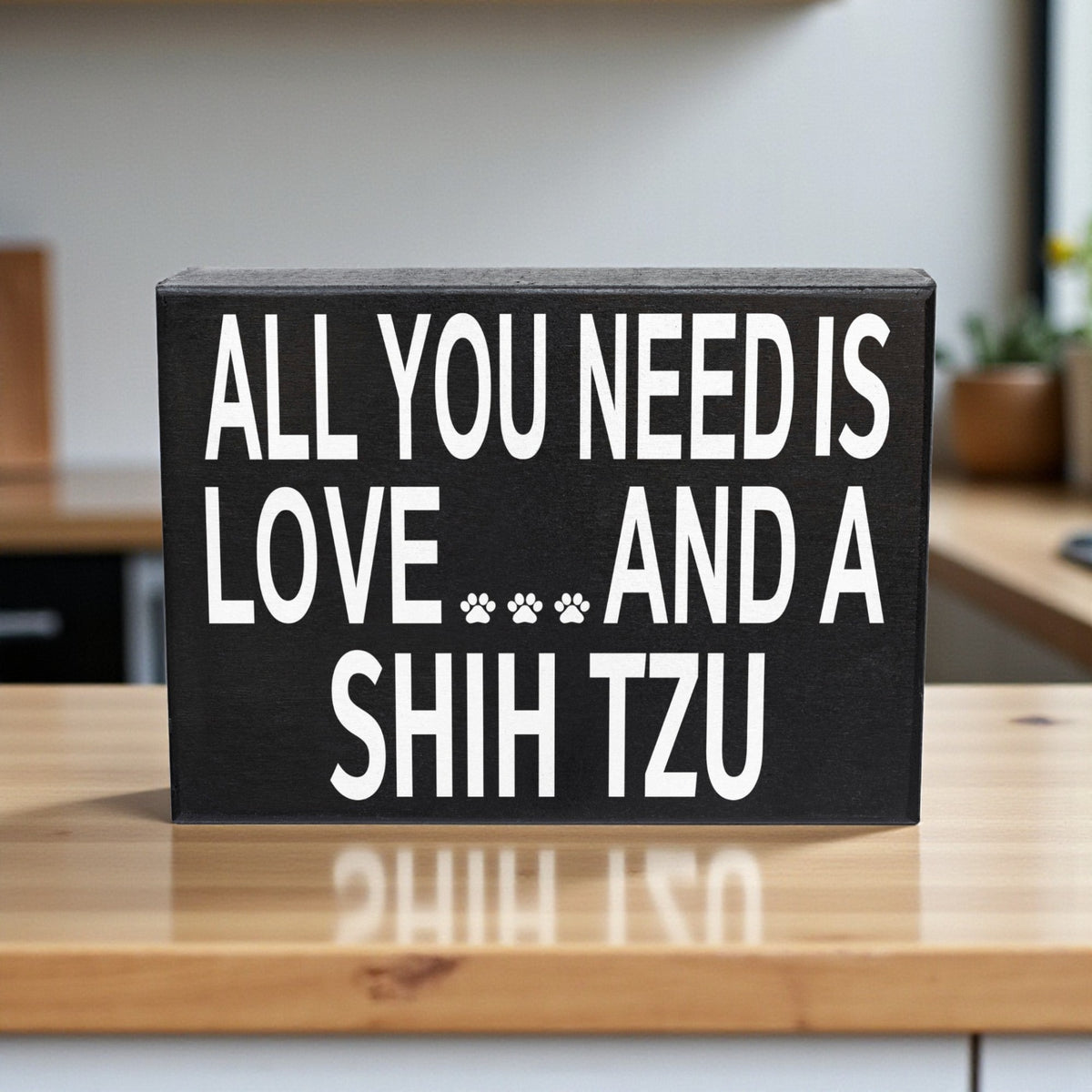 Decorative sign with text 'All you need is love and a Shih Tzu' on a wooden surface.
