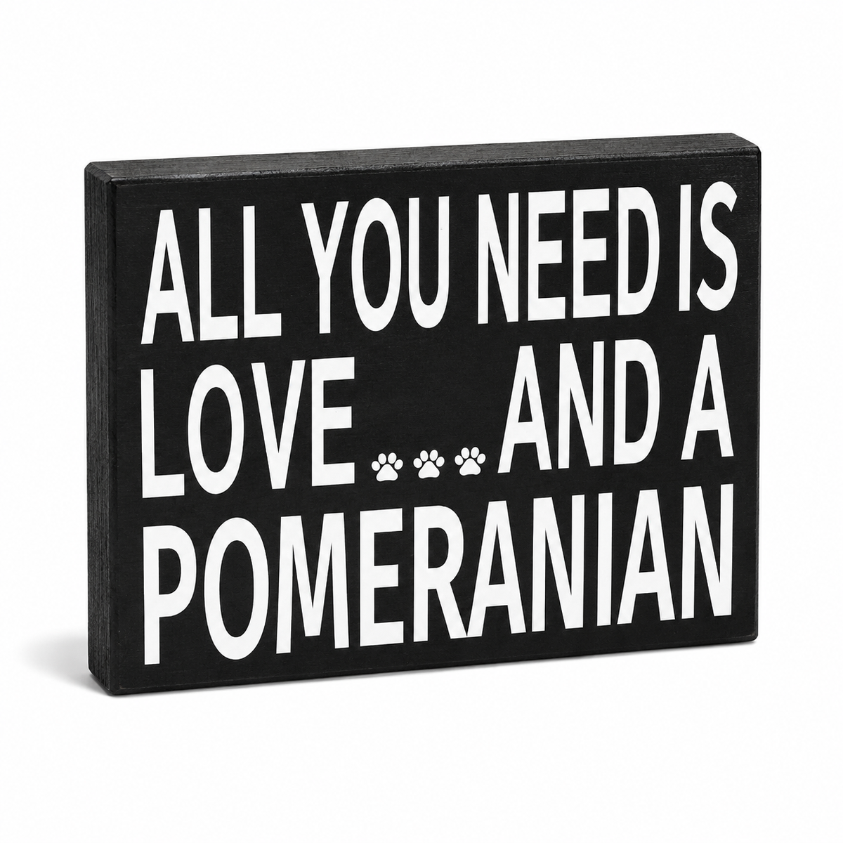 A rectangular black decorative sign with bold white text reading 'ALL YOU NEED IS LOVE.