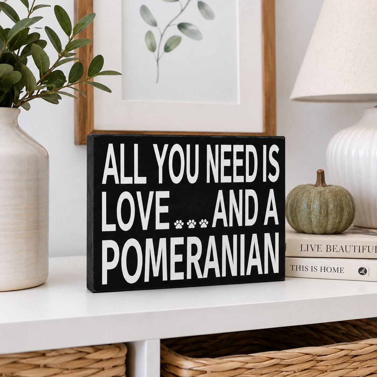 A black rectangular decorative sign with bold white text reading 'ALL YOU NEED IS LOVE.