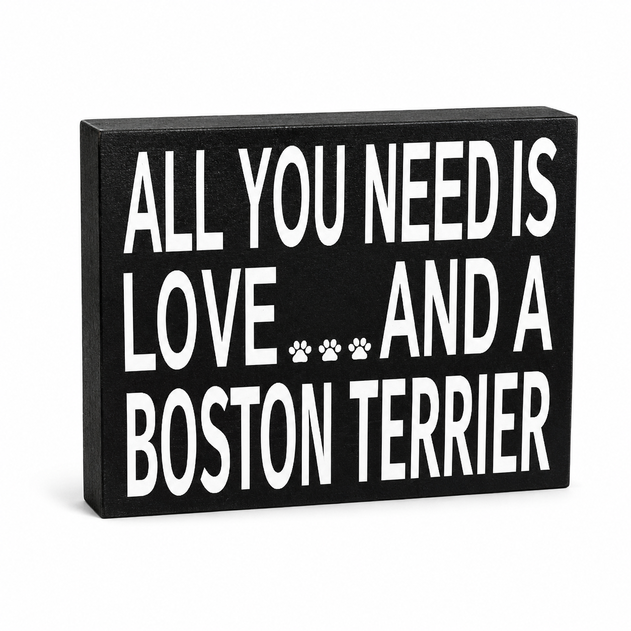 A rectangular black wooden sign with bold white text reading 'ALL YOU NEED IS LOVE.