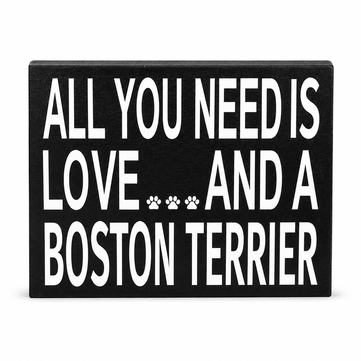 A rectangular black sign with bold white text reading 'ALL YOU NEED IS LOVE.