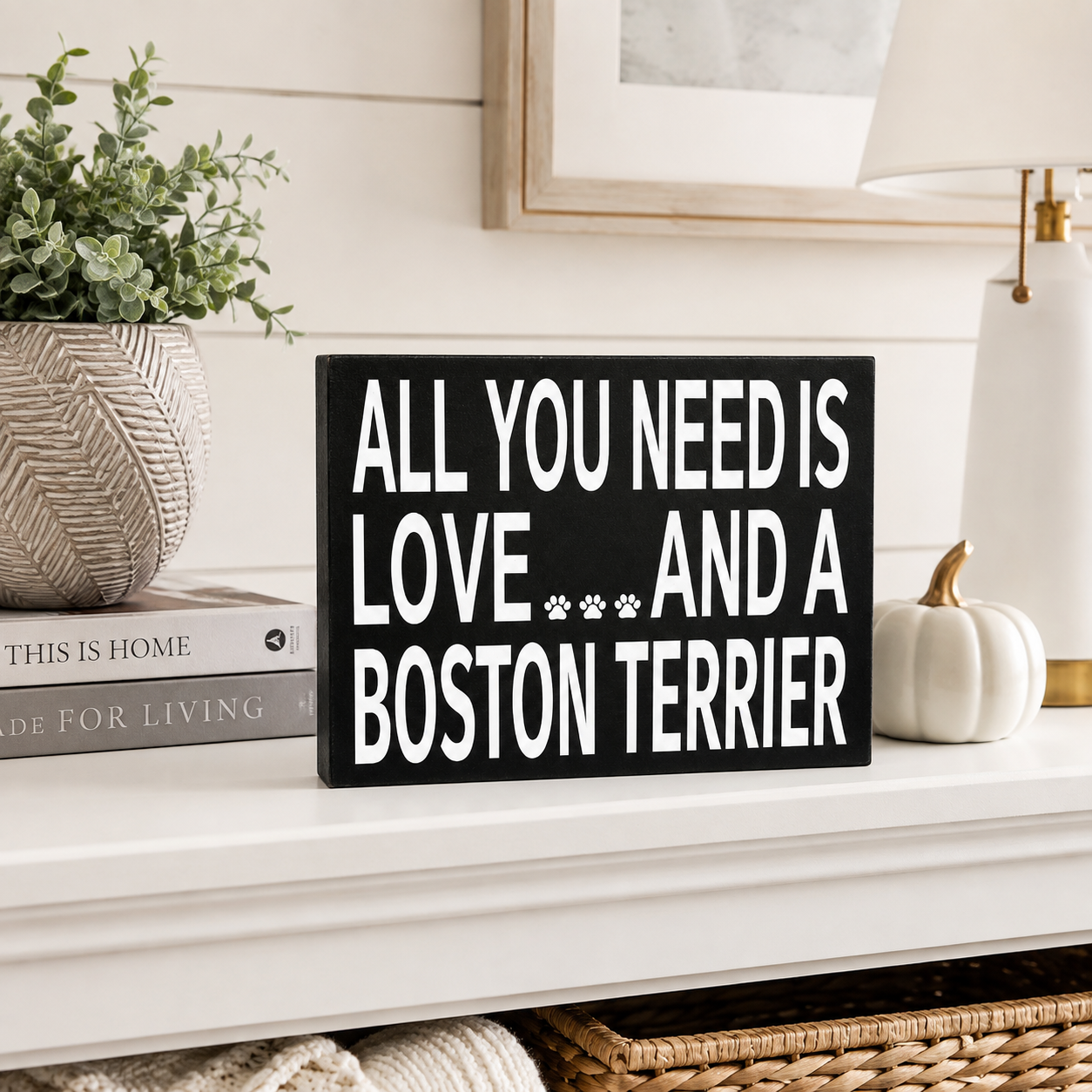 A black rectangular decorative sign with bold white text reading 'ALL YOU NEED IS LOVE.