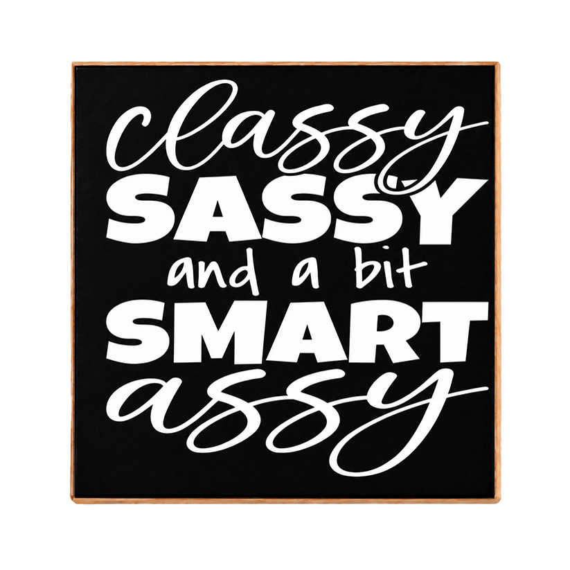 A square decorative sign with a black face and light wood border, featuring the phrase 'Classy Sassy and a bit Smart Assy' in white lettering, shown on a plain white background.