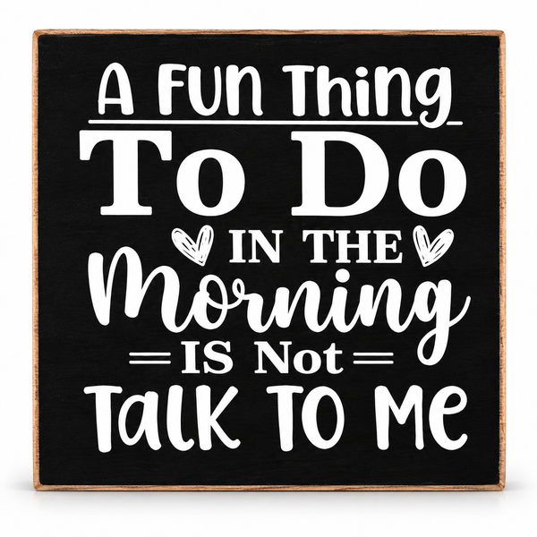 A square decorative sign with a black face, white typographic quote reading 'A Fun Thing To Do In The Morning Is Not Talk To Me,' and a light natural wood border, shown on a plain white background.