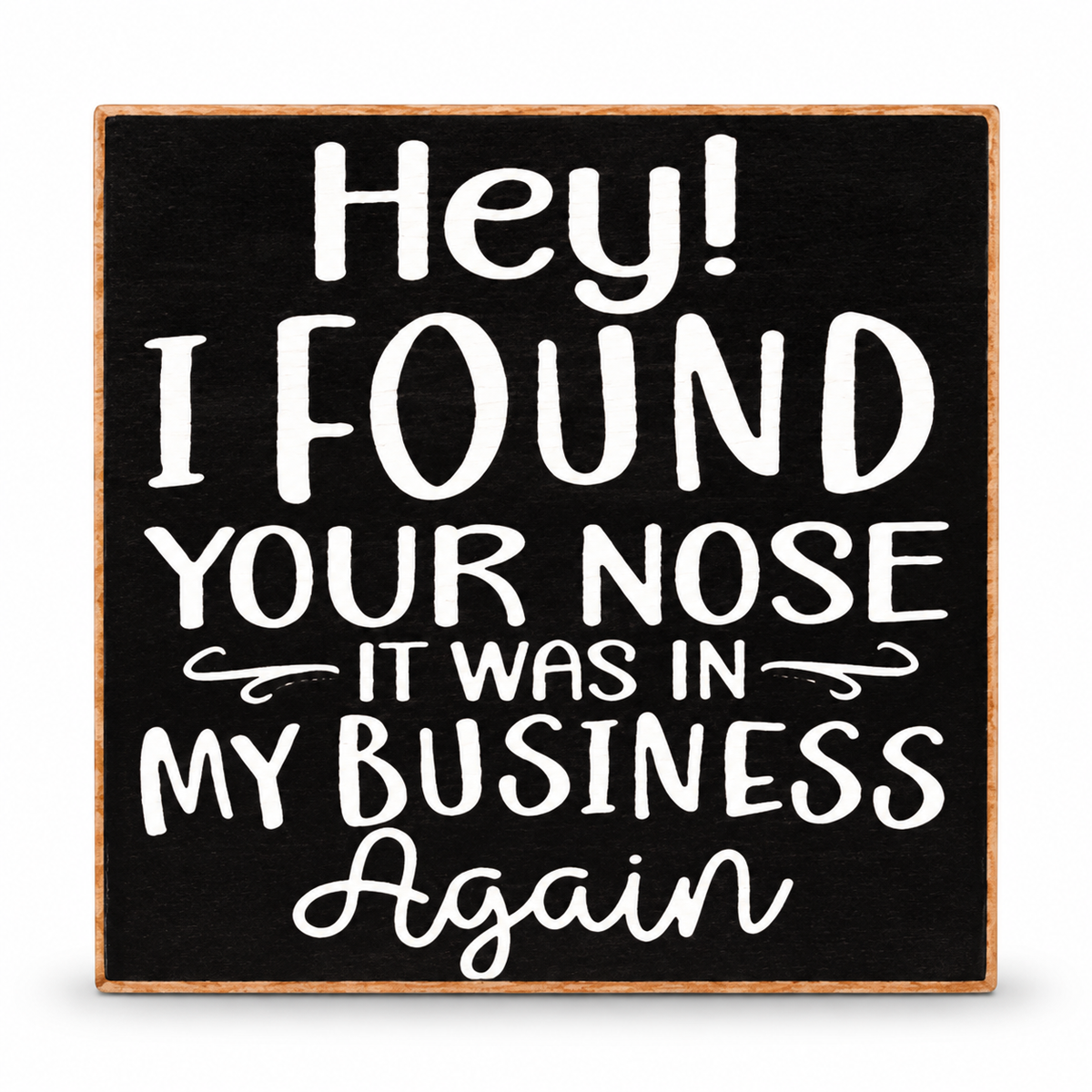 A square black decorative sign with a light wood border and white hand-lettered text that reads, 'Hey! I FOUND YOUR NOSE IT WAS IN MY BUSINESS Again.'.