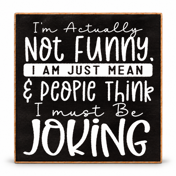 Square decorative sign with a black chalkboard-style face, light wood border, and white hand-painted text that reads, 'I'm Actually Not Funny. I AM JUST MEAN & PEOPLE THINK I must Be JOKING.