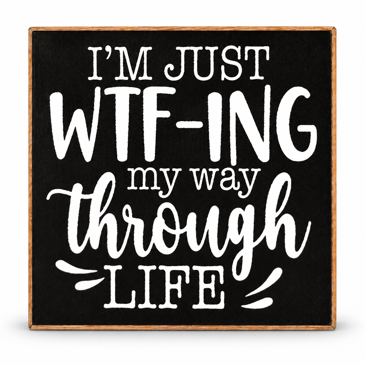 A square decorative sign with a black face and natural wood border, featuring the phrase “I’M JUST WTF-ING my way through LIFE” in white lettering, shown on a plain white background.