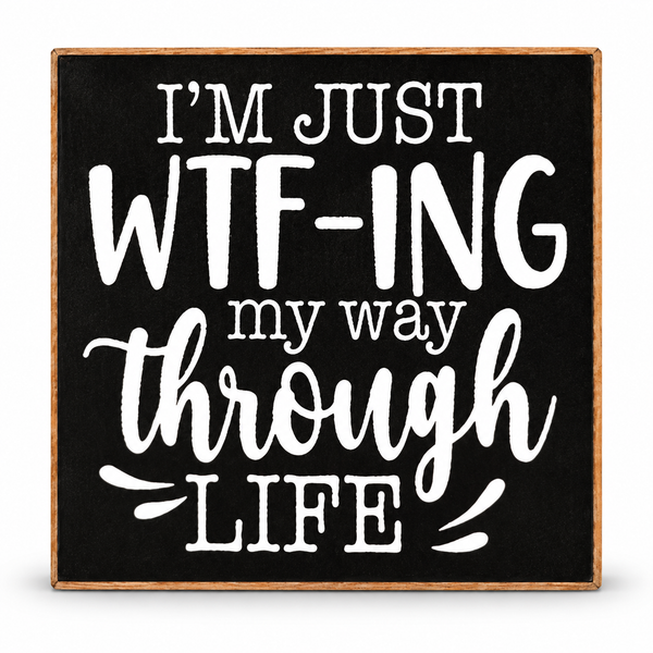 A square decorative sign with a black face and natural wood border, featuring the phrase “I’M JUST WTF-ING my way through LIFE” in white lettering, shown on a plain white background.