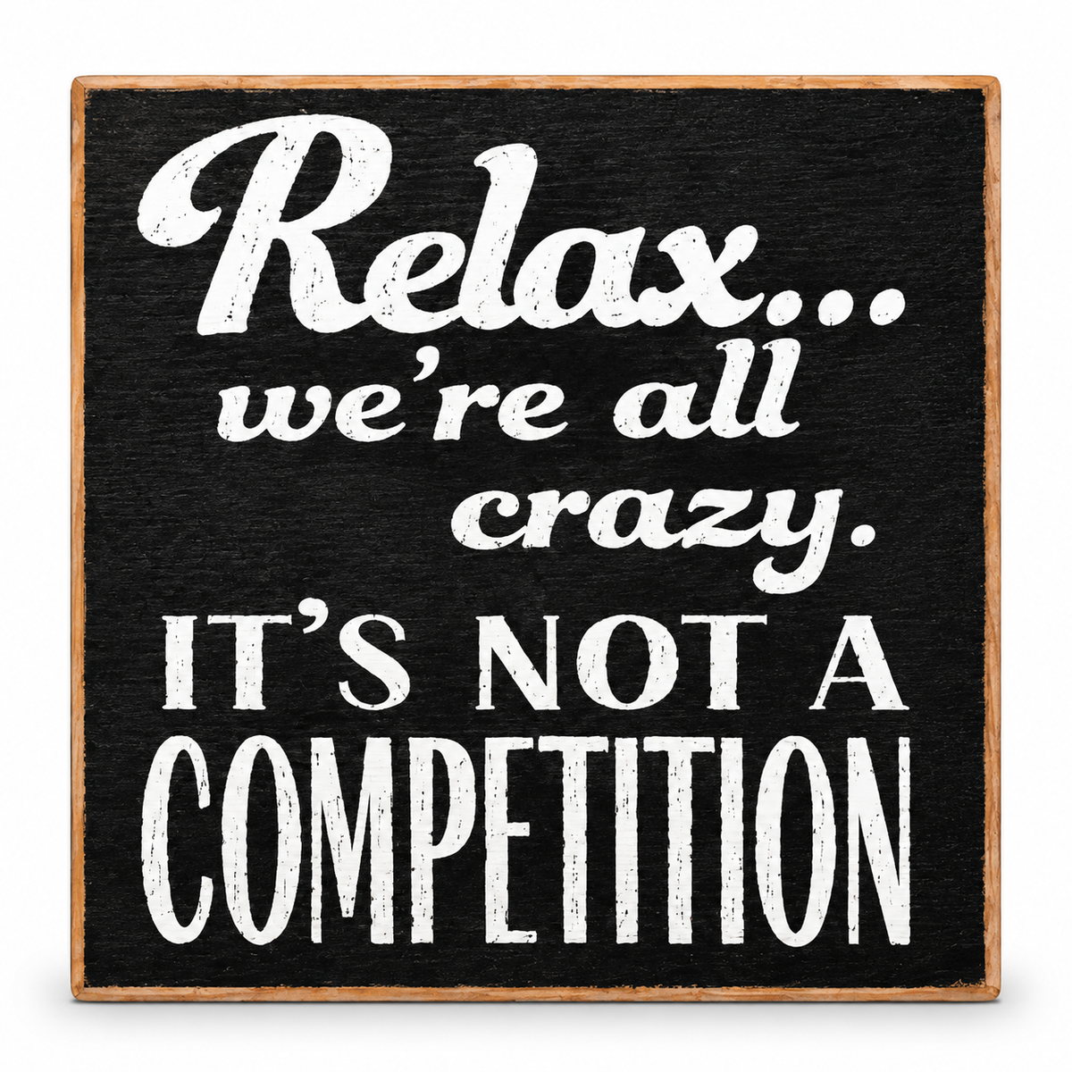 A square decorative sign with a black textured face and natural wood border, featuring the phrase 'Relax.