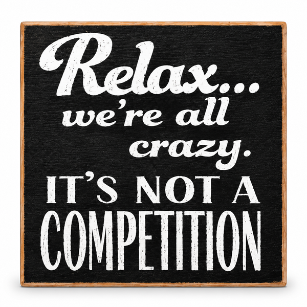 A square decorative sign with a black textured face and natural wood border, featuring the phrase 'Relax.