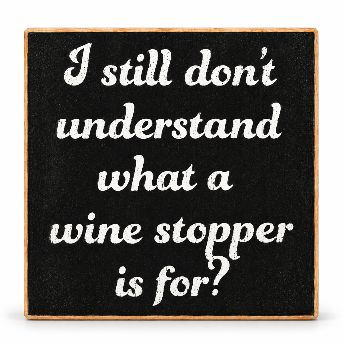 A square decorative sign with a black chalkboard-style face and a natural wood border, featuring the white text, 'I still don't understand what a wine stopper is for?'.