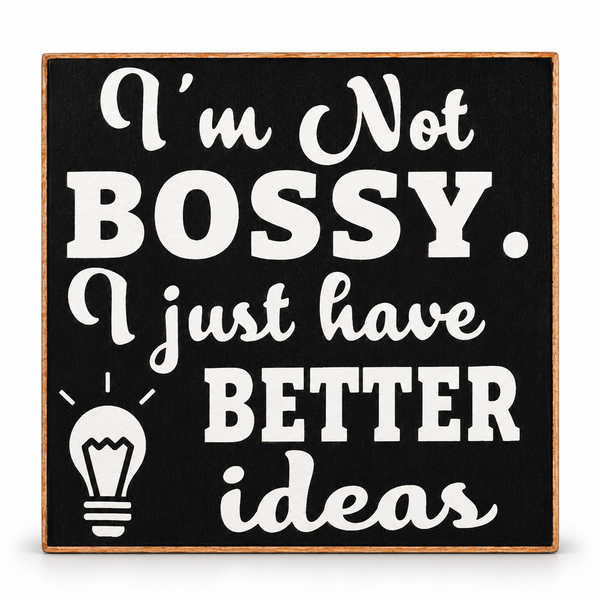 Square decorative sign with a black face, white text reading “I’m Not BOSSY. I just have BETTER ideas,” and a white lightbulb graphic, surrounded by a natural wood border on a white background.