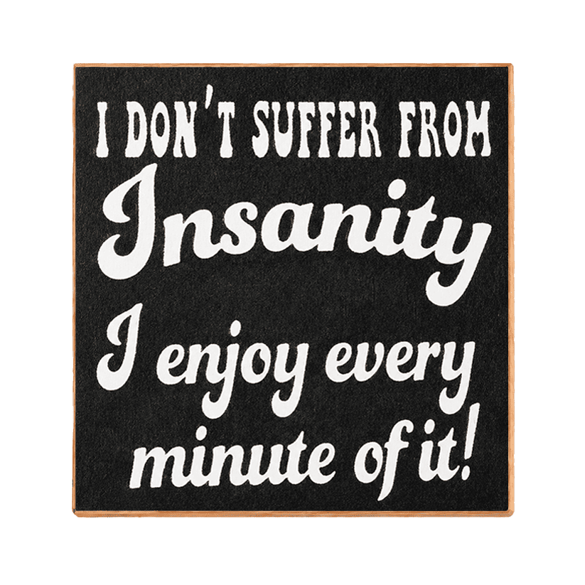A square black decorative sign with a light wood border and white text that reads, 'I DON'T SUFFER FROM Insanity I enjoy every minute of it!' on a plain white background.