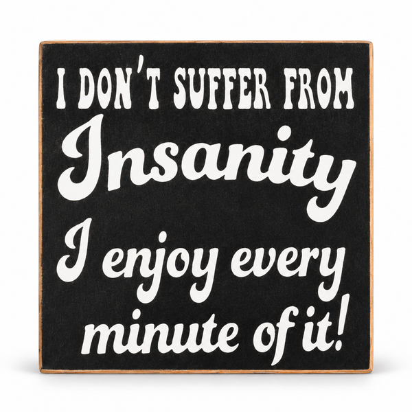 A square black decorative sign with a light wood border and white text that reads, 'I DON'T SUFFER FROM Insanity I enjoy every minute of it!' on a white background.