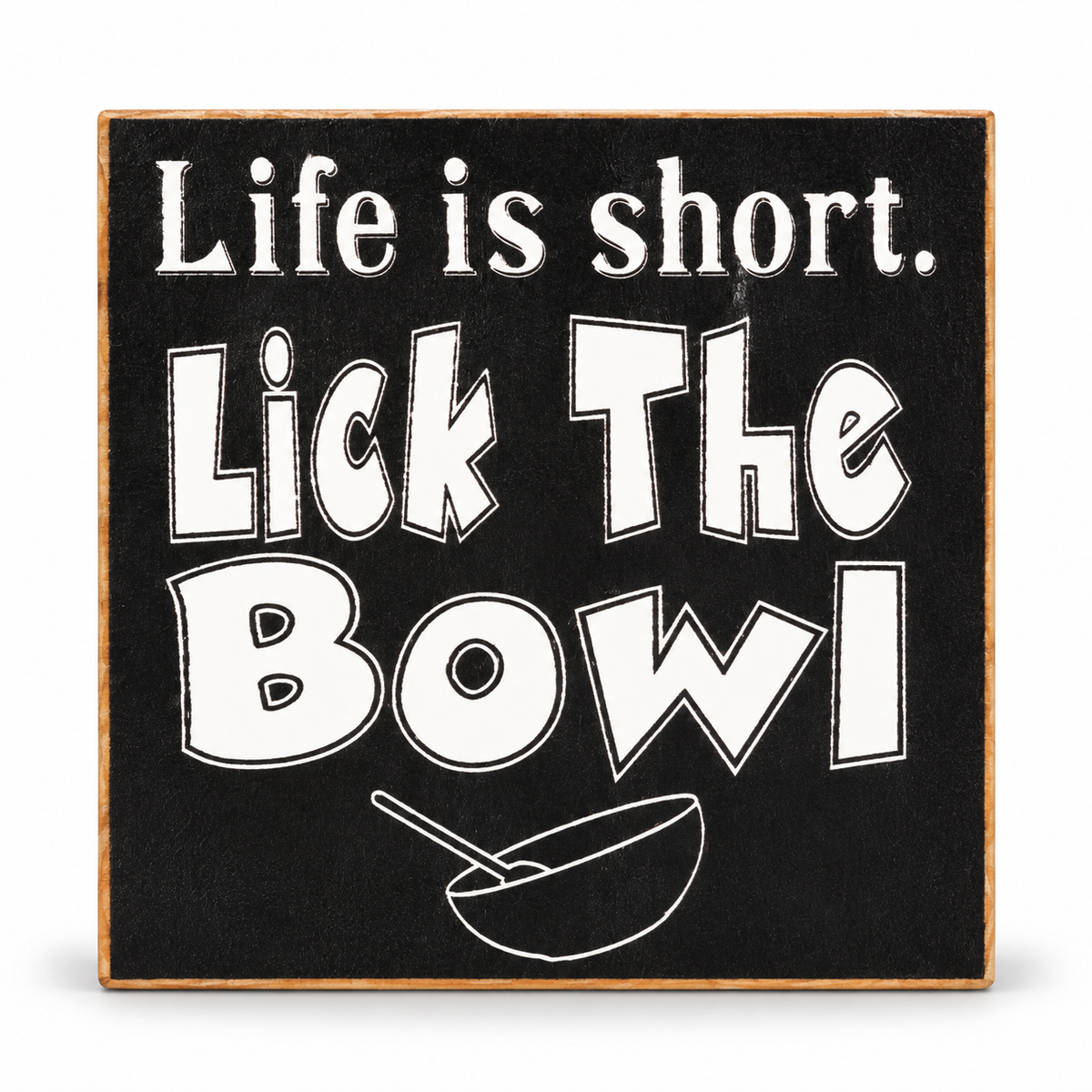 A square decorative sign with a black face, white text reading 'Life is short. Lick The Bowl,' and a white bowl-and-stirrer illustration, with a natural wood edge around it, shown on a white background.