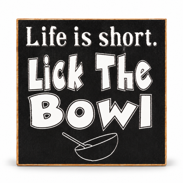 A square decorative sign with a black face, white text reading 'Life is short. Lick The Bowl,' and a white bowl-and-stirrer illustration, with a natural wood edge around it, shown on a white background.
