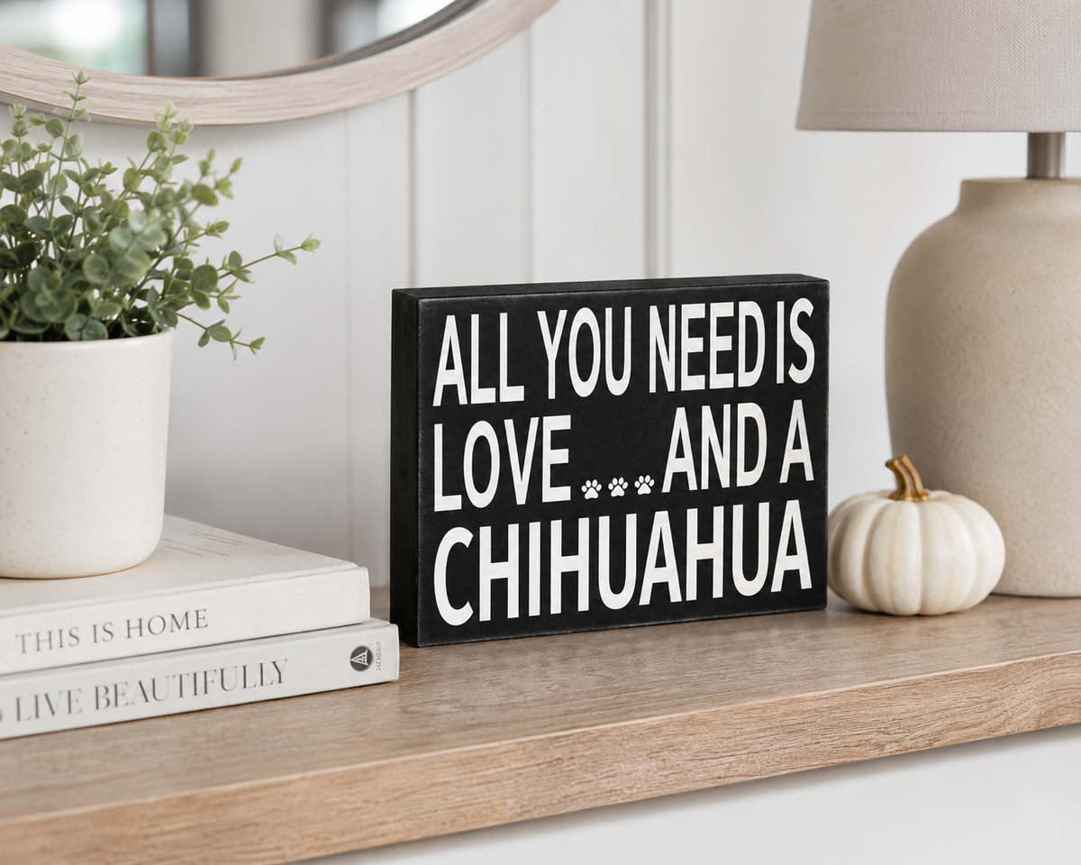A black rectangular decorative sign with white text reading 'ALL YOU NEED IS LOVE.