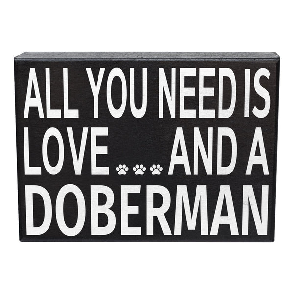 A rectangular black decorative sign with bold white text reading 'ALL YOU NEED IS LOVE.