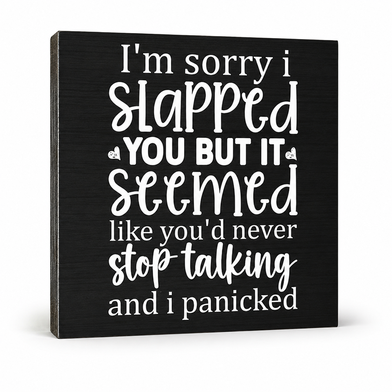 A square black decorative sign with white text that reads, 'I'm sorry i Slapped YOU BUT IT seemed like you'd never stop talking and i panicked,' shown on a clean white background.