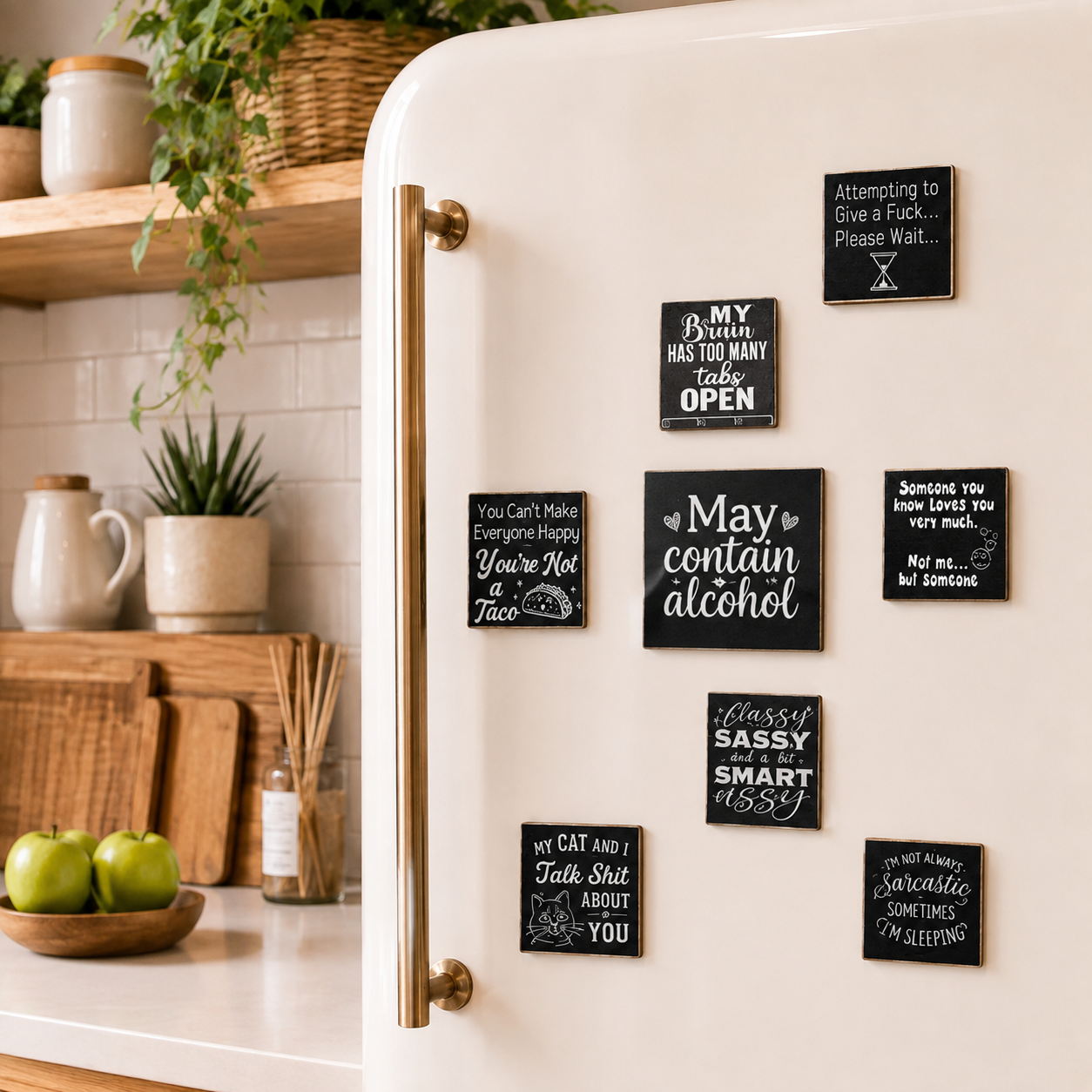 A cream-colored retro-style refrigerator in a kitchen setting, decorated with multiple black square magnets featuring humorous and witty sayings in white chalk-style lettering.