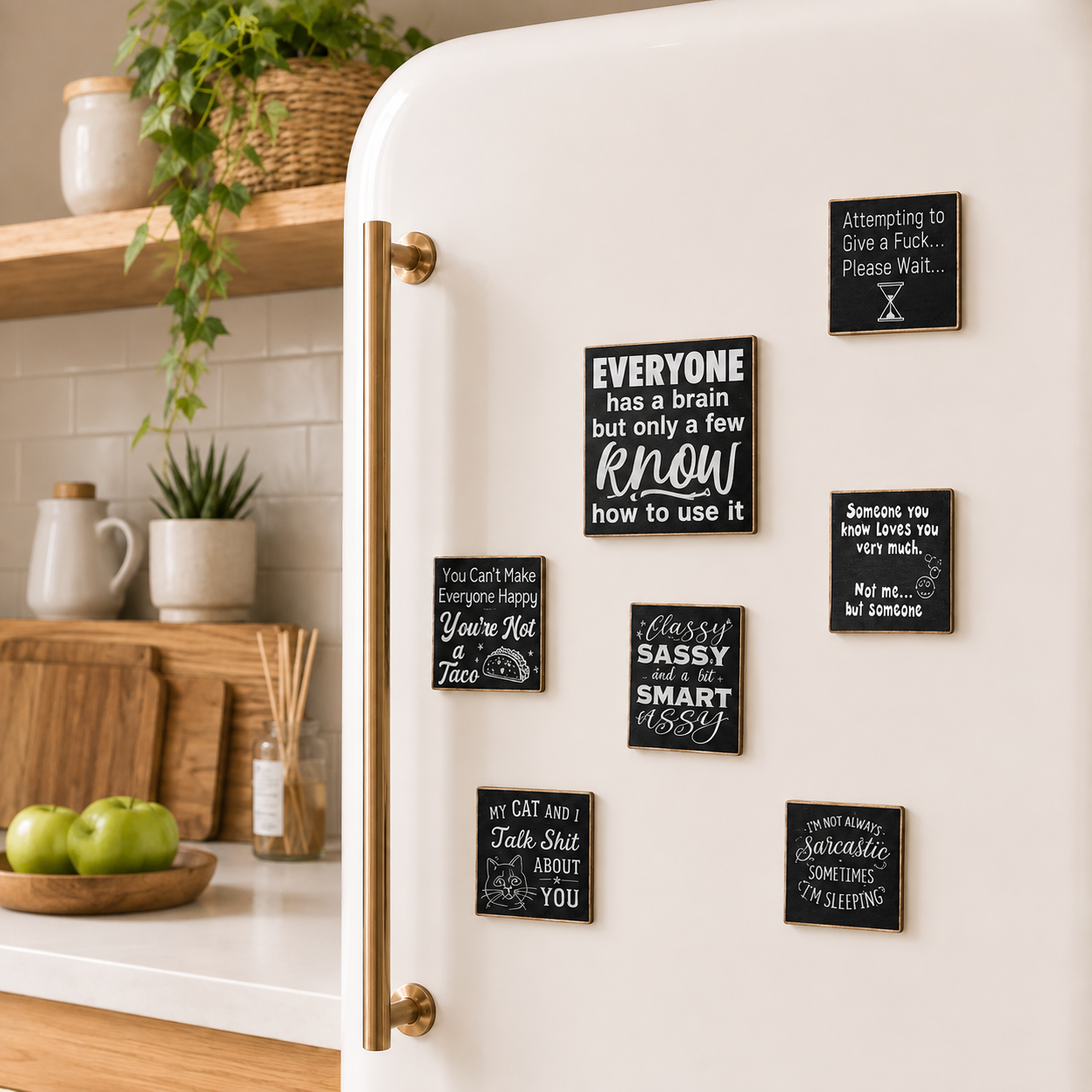 A white refrigerator in a bright kitchen setting, decorated with multiple small black square magnets featuring white handwritten-style quotes and sayings.