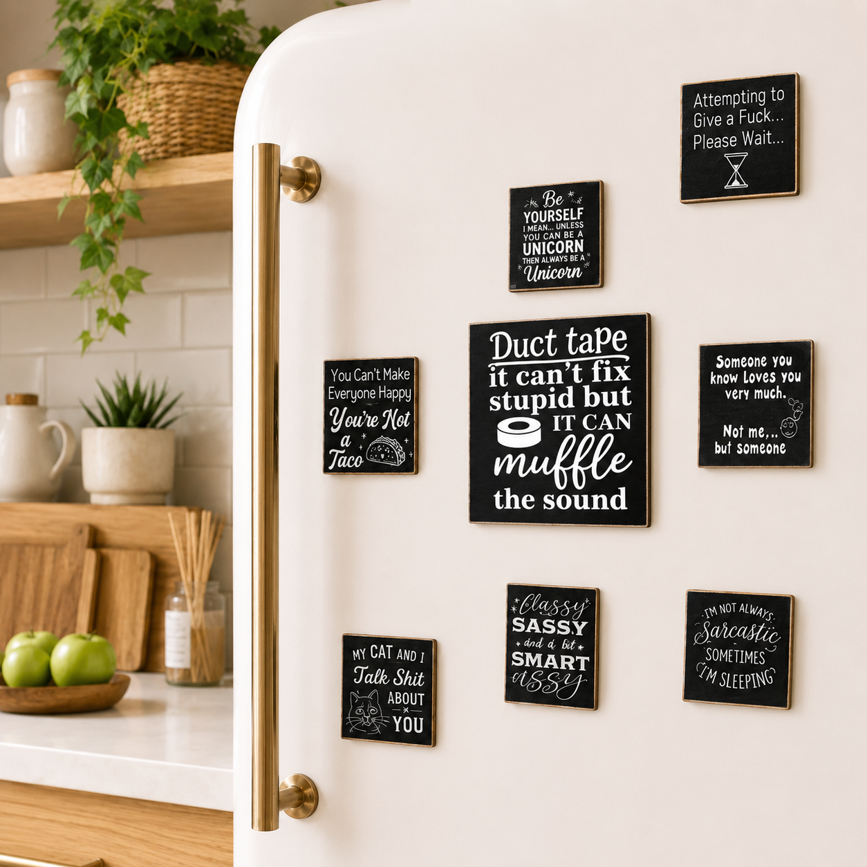 A set of black rectangular refrigerator magnets with white handwritten-style humorous quotes, shown attached to a white retro-style refrigerator in a bright kitchen setting.