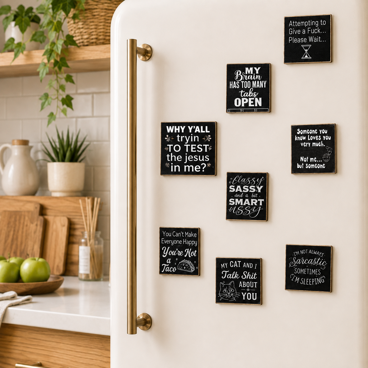 A set of dark square refrigerator magnets with white handwritten-style quotes and drawings, arranged on a white retro-style refrigerator in a bright kitchen setting.