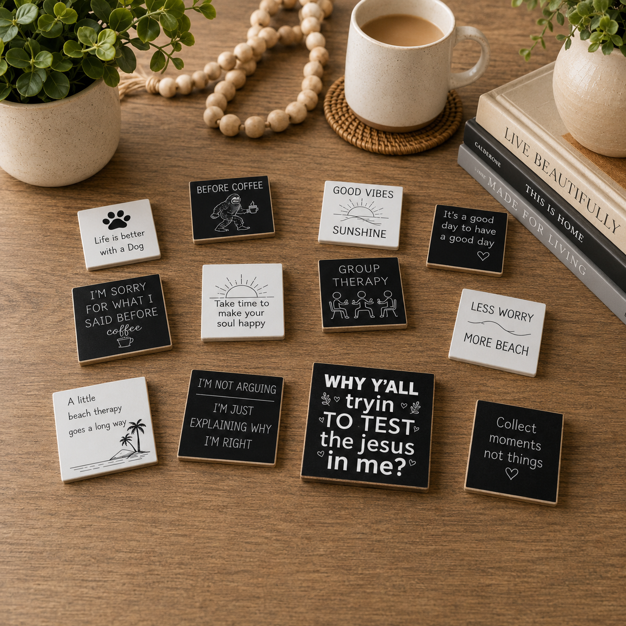 A set of small square ceramic tiles with black and white inspirational quotes and illustrations, arranged on a wooden tabletop next to a mug, books, and plants.