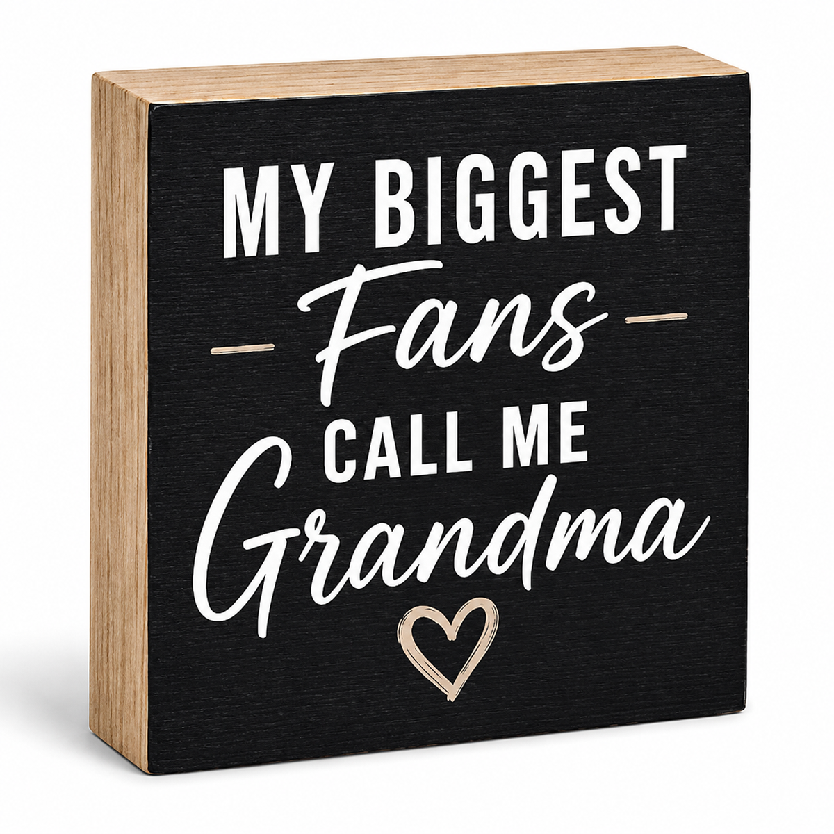 A square decorative wooden sign with a black front and natural wood sides, featuring the phrase 'MY BIGGEST Fans CALL ME Grandma' in white lettering with a small white heart outline, shown on a white background.