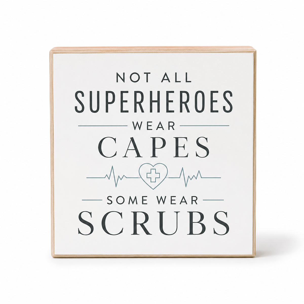 A square decorative wooden sign with a light natural wood frame and a white face, printed with the text 'NOT ALL SUPERHEROES WEAR CAPES SOME WEAR SCRUBS' in dark gray lettering with a light blue heart monitor line and medical cross symbol in the center, shown on a white background.